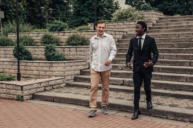 Portrait de deux jeunes hommes d'affaires confiants descendant les escaliers et parlant