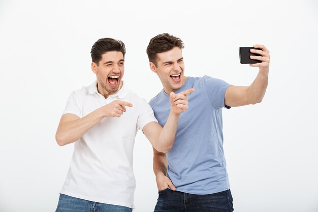 Portrait de deux jeunes hommes joyeux, pointant le doigt