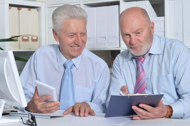 Portrait de deux personnes d'affaires senior travaillant avec un ordinateur sur la table