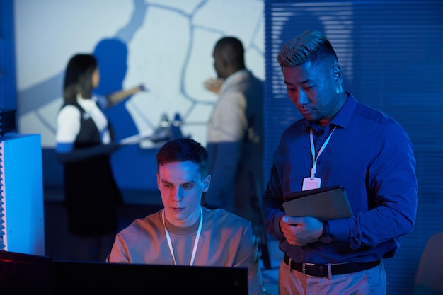 Portrait de deux personnes travaillant dans un centre de contrôle de mission avec des tons bleus et rouges futuristes