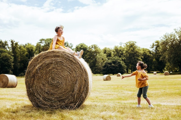 Portrait de deux petites filles assises sur une botte de foin dans un champ à la lumière du jour ensoleillé souriant et riant meilleurs amis