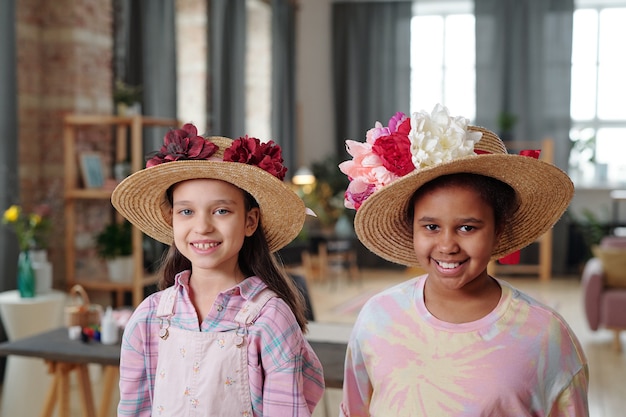 Portrait de deux petites filles dans de beaux chapeaux avec des fleurs souriant à la caméra