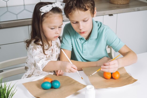 Portrait de deux petits enfants joyeux enthousiastes garçon et fille pinceau peinture couleur oeufs de Pâques vacances en famille tradion