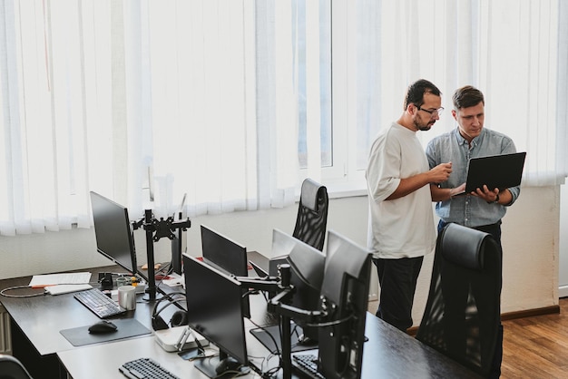 Portrait de deux programmeurs masculins professionnels travaillant sur l'ordinateur dans divers bureaux Technologies informatiques modernes développement de programmes d'intelligence artificielle applications et concept de jeux vidéo