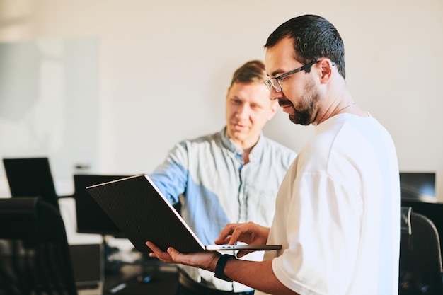 Portrait de deux programmeurs masculins professionnels travaillant sur l'ordinateur dans divers bureaux Technologies informatiques modernes développement de programmes d'intelligence artificielle applications et concept de jeux vidéo