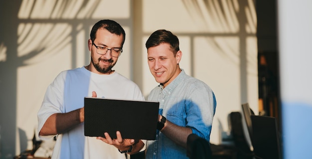 Portrait de deux programmeurs masculins professionnels travaillant sur l'ordinateur dans divers bureaux Technologies informatiques modernes développement de programmes d'intelligence artificielle applications et concept de jeux vidéo