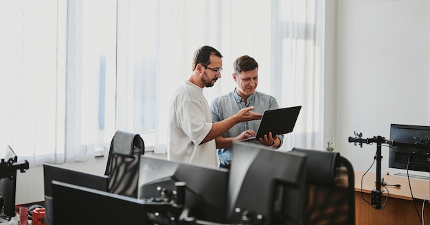 Portrait de deux programmeurs professionnels masculins travaillant sur ordinateur dans divers bureaux Technologies informatiques modernes Développement d'applications de programmes d'intelligence artificielle et concept de jeux vidéo