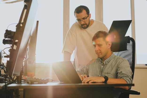 Portrait de deux programmeurs professionnels masculins travaillant sur ordinateur dans divers bureaux Technologies informatiques modernes Développement d'applications de programmes d'intelligence artificielle et concept de jeux vidéo