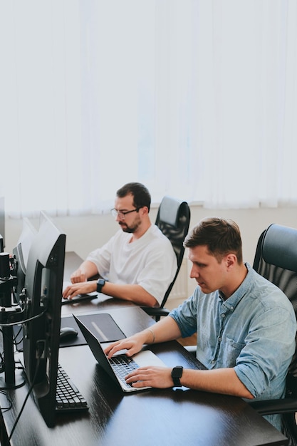 Portrait de deux programmeurs professionnels masculins travaillant sur ordinateur dans divers bureaux Technologies informatiques modernes Développement d'applications de programmes d'intelligence artificielle et concept de jeux vidéo