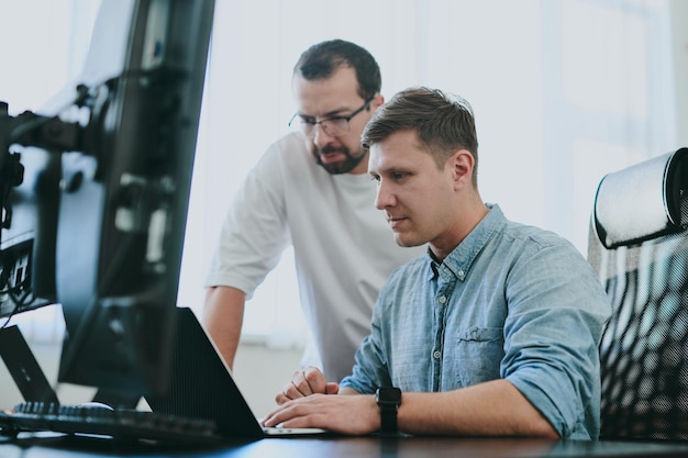 Portrait de deux programmeurs professionnels masculins travaillant sur ordinateur dans divers bureaux Technologies informatiques modernes Développement d'applications de programmes d'intelligence artificielle et concept de jeux vidéo