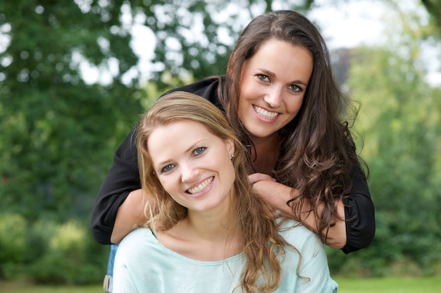 Portrait de deux soeurs adultes souriant ensemble à l&#39;extérieur