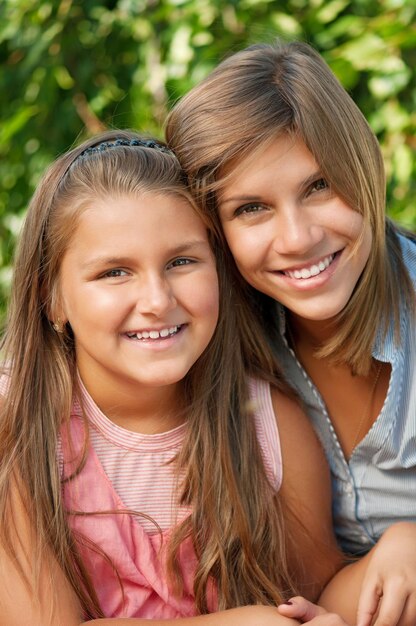 Photo portrait de deux sœurs heureuses dans un parc en plein air