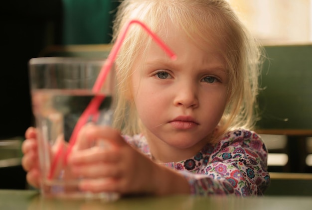 Portrait d'une douce belle petite fille buvant un verre d'eau