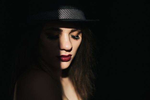 Portrait dramatique de sexy jeune fille au chapeau noir avec rouge à lèvres