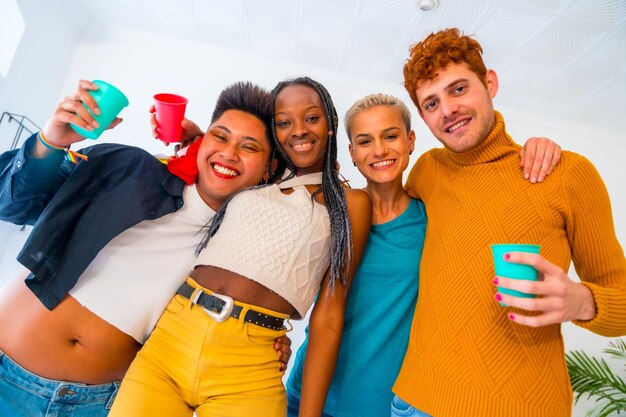 Portrait de drapeau arc-en-ciel lgbt fierté LGBT d'un groupe d'amis dansant dans une maison à la fête