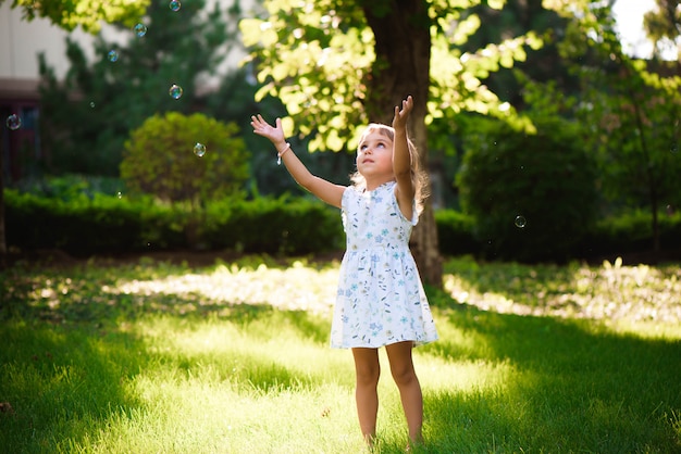 Portrait de drôle belle petite fille soufflant des bulles de savon