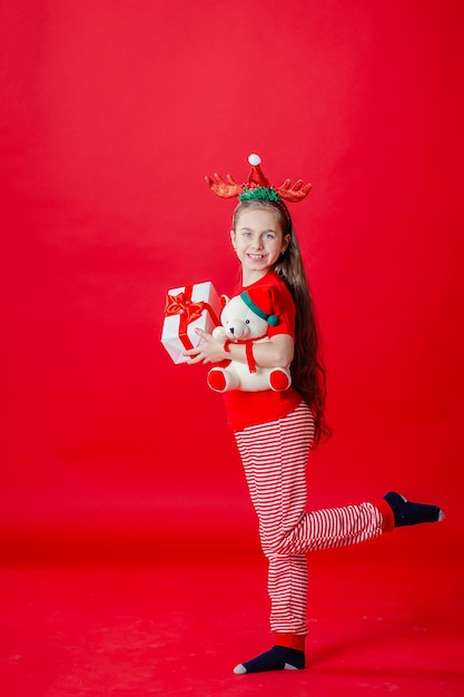 Portrait d'une drôle de fille joyeuse avec un bandage de cornes sur la tête étreignant un fond rouge isolé