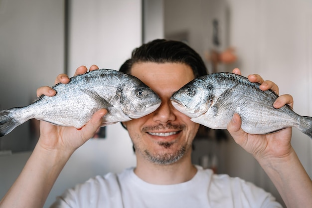 Photo portrait drôle d'un homme tenant un poisson dans la cuisine