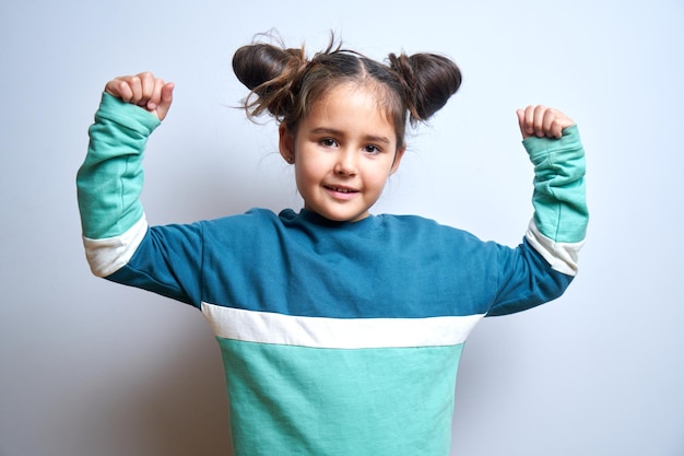 Portrait d'une drôle de petite fille brune qui s'amuse à se réjouir isolée sur fond blanc