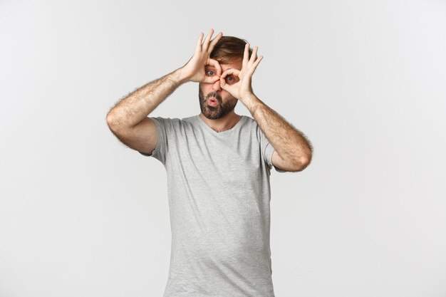 Portrait de drôle de type caucasien faisant des grimaces et se moquant de quelqu'un, debout sur fond blanc