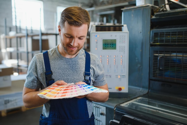 Portrait drôle de typographe debout avec des échantillons de couleurs à la fabrication d'impression