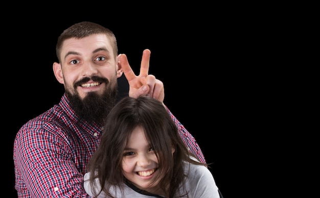 Portrait du beau père et de sa jolie fille s'embrassant, regardant la caméra et souriant.