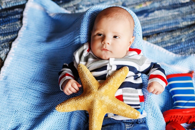 Portrait du beau petit garçon sur une couverture tricotée bleue