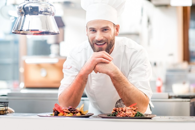 Portrait du chef cuisinier en uniforme avec un délicieux plat préparé à la cuisine du restaurant