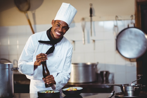 Portrait du chef saupoudrer de poivre sur un repas