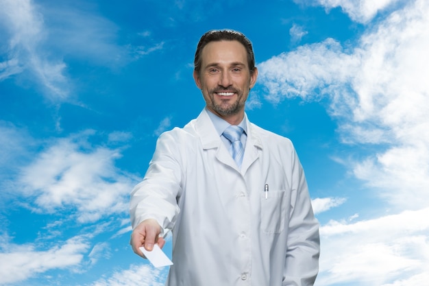 Portrait du docteur vous donnant sa carte de visite. Ciel bleu avec des nuages en arrière-plan.