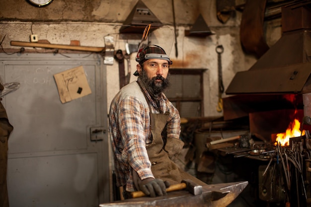 Le portrait du forgeron barbu se préparant à travailler dans son atelier Petite entreprise Maître artisan forgeron