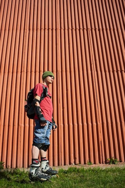 Le portrait du gars sur les rouleaux contre le mur rouge