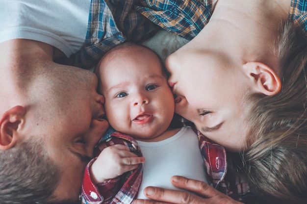 Photo portrait du père et de la mère avec un fils de trois mois. embrasser le petit fils. jeune famille heureuse. mise en quarantaine dans le cercle familial