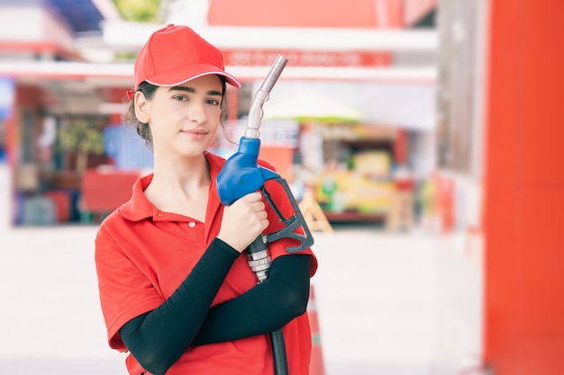 Portrait du personnel de la station-service femmes heureuses souriantes avec une buse de carburant pour le travail de service de remplissage d'essence de voiture.