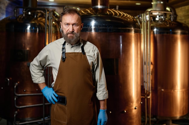 Portrait du propriétaire de la brasserie portant un tablier avec les bras croisés