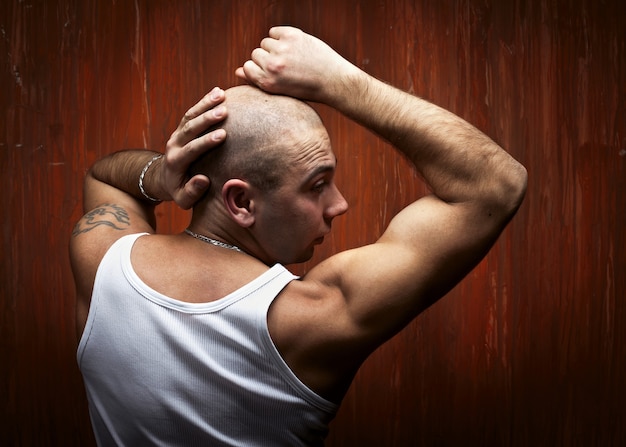 Portrait du sportif chauve en chemise blanche, devant un mur rouge.