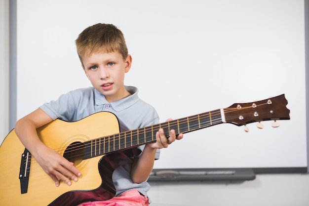 Portrait d'écolier jouant de la guitare en classe