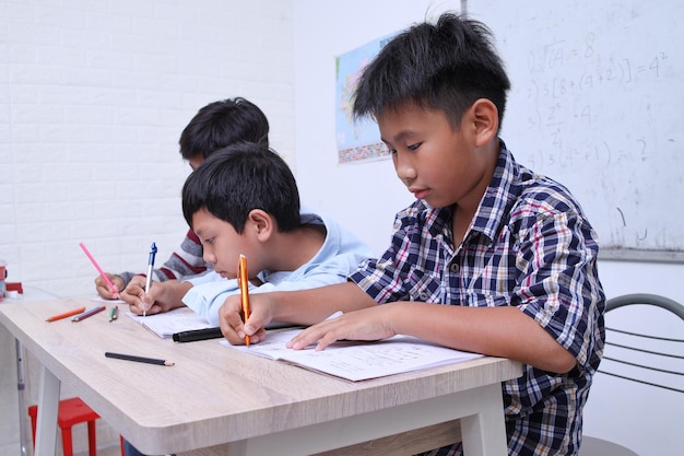 Portrait d'écolier mignon divers étudiant ensemble en classe écrivant sur un livre