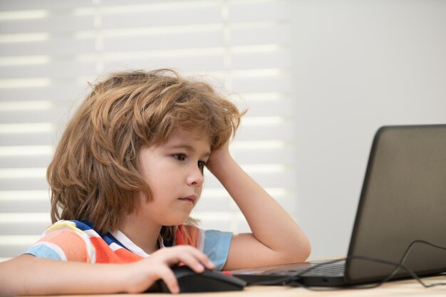 Portrait d'écolier regardant l'ordinateur portable pendant la leçon. L'éducation et l'apprentissage pour l'enfant.