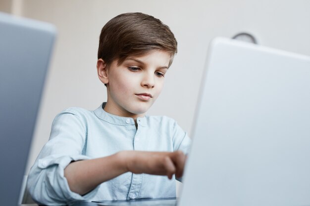 Portrait d'écolier utilisant un ordinateur portable pendant les cours d'informatique à l'école, espace de copie