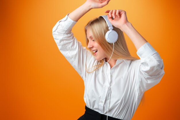 Portrait d'une écolière adolescente moderne et heureuse avec un casque sur fond orange