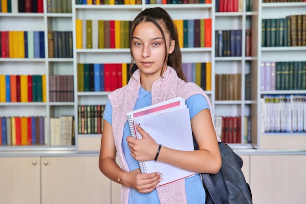 Portrait d'une écolière adolescente regardant l'arrière-plan intérieur de la bibliothèque de la caméra