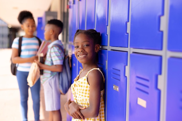 Portrait d'une écolière afro-américaine heureuse debout à côté du casier à l'école