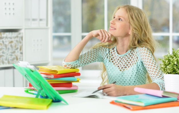 Portrait d'une écolière assise au bureau et étudiant