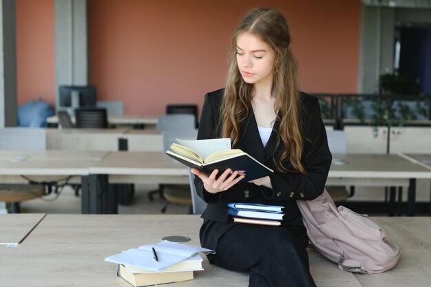 Portrait d'une écolière debout dans la salle de classe avec un livre dans les mains