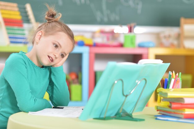 Portrait d'écolière heureuse mignonne faisant ses devoirs