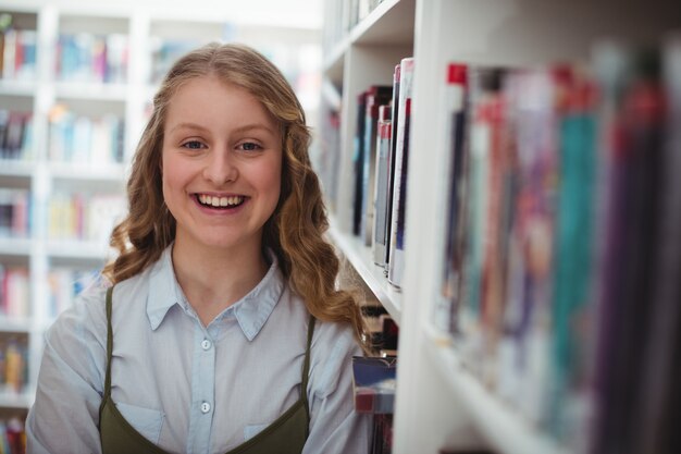 Portrait d'écolière heureux debout dans la bibliothèque