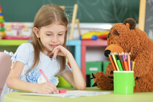 Portrait d'écolière mignonne assise et dessinant