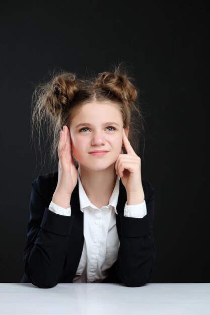 Portrait d'une écolière de petite fille sur fond noir