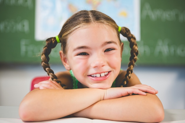 Portrait d'écolière s'appuyant sur un livre en classe